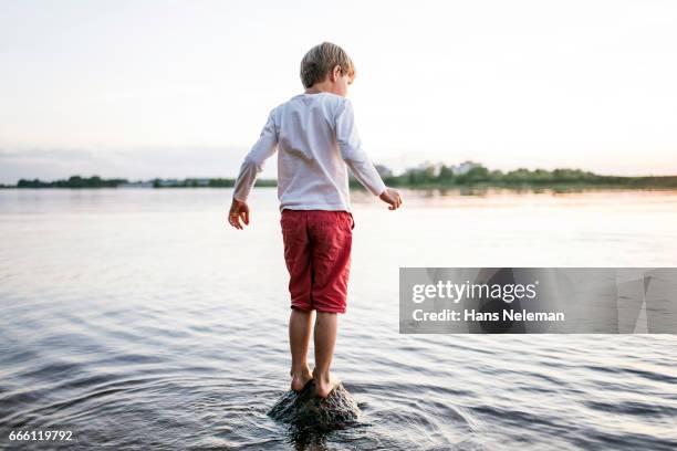 kid standing on the rock in a river - red shorts stock pictures, royalty-free photos & images