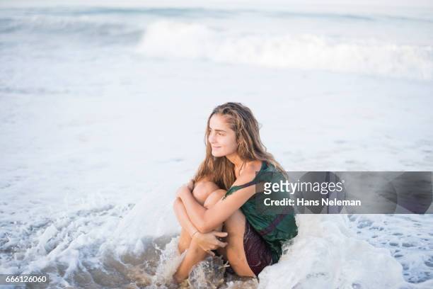 view of playful woman enjoying at beach - hugging knees stock pictures, royalty-free photos & images