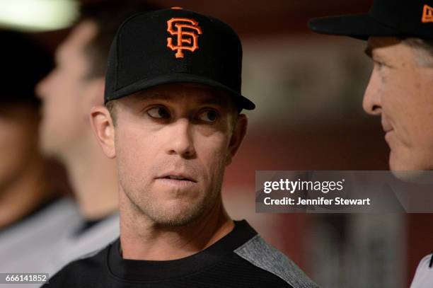 Aaron Hill of the San Francisco Giants talks with pitching coach Dave Righetti in the dugout during the MLB game against the Arizona Diamondbacks at...