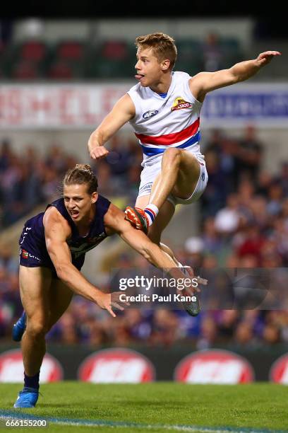 Nathan Fyfe of the Dockers attempts to smother the kick by Lachie Hunter of the Bulldogs during the round three AFL match between the Fremantle...