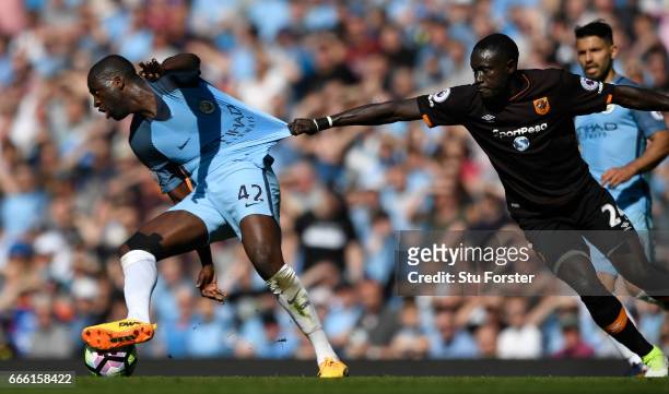 Hull City player Oumar Niasse grabs hold of Manchester City player Yaya Toure during the Premier League match between Manchester City and Hull City...