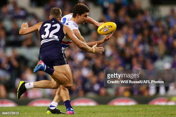 Tom Liberatore of the Bulldogs handballs under pressure from Stephen Hill of the Dockers during the round three AFL match between the Fremantle...