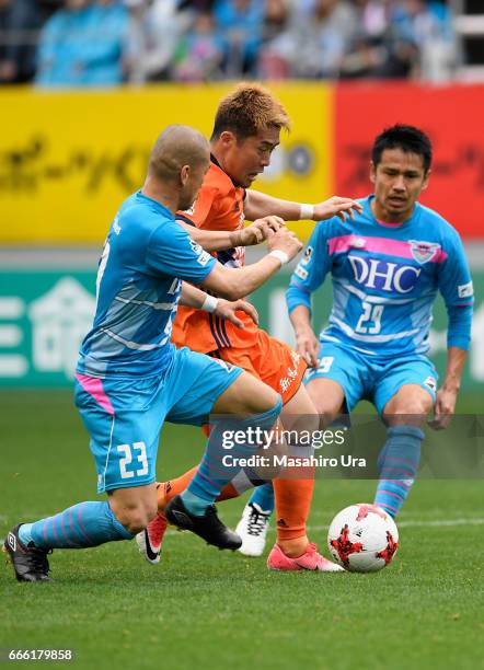 Ryohei Yamazaki of Albirex Niigata competes for the ball against Yutaka Yoshida and Hiroyuki Taniguchi of Sagan Tosu during the J.League J1 match...