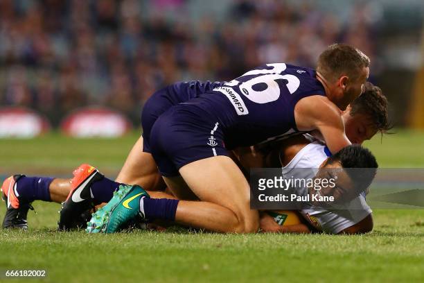 Lin Jong of the Bulldogs gets tackled by Ethan Hughes and Ed Langdon of the Dockers during the round three AFL match between the Fremantle Dockers...