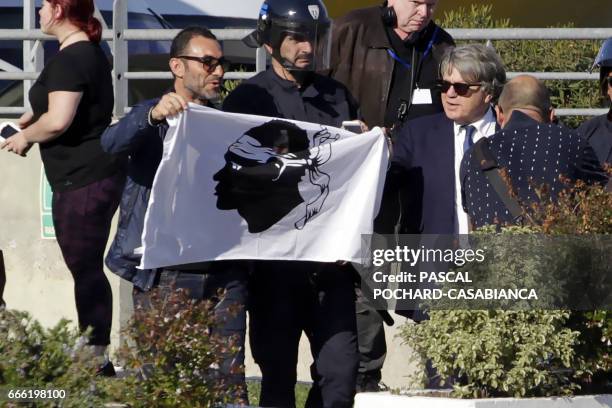 French FN member of parliament Gilbert Collard holds a Corsican flag as people demonstrate after a meeting of the French far-right Front National...