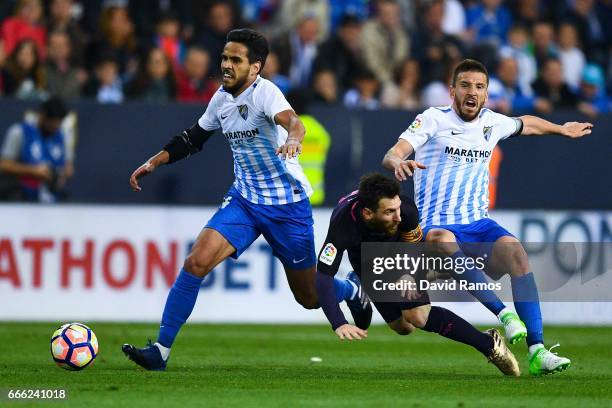 Lionel Messi of FC Barcelona is brought down by Jose Luis Garcia Recio and Ignacio Camacho of Malaga CF during the La Liga match between Malaga CF...