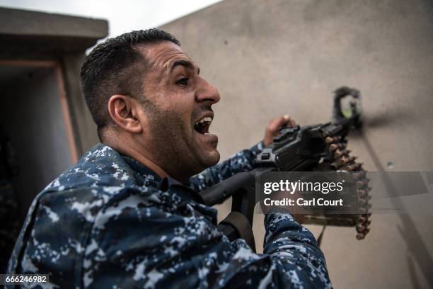 An Iraqi federal policeman shouts as he fires a machine gun at a nearby Islamic State position during fighting in west Mosul on April 8, 2017 in...