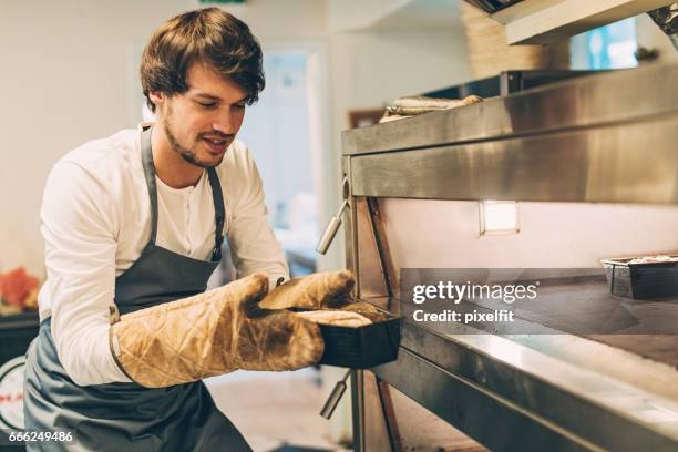 das heiße brot herausnehmen vorsichtig - inserting stock-fotos und bilder