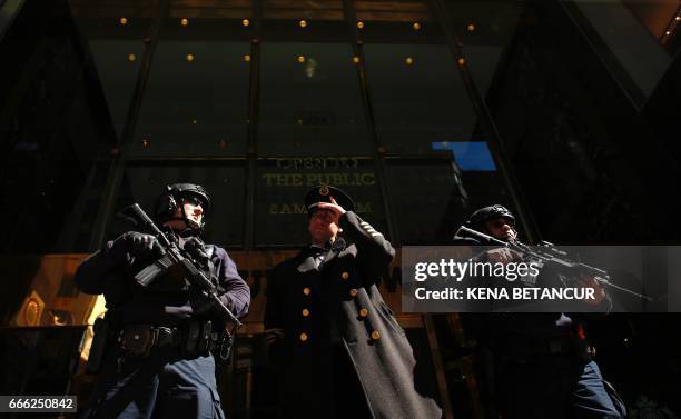 Armed NYPD officers and a Doorman stand guard outside the Trump Tower as people rally nearby in support of immigrants workers on April 08, 2017 in...