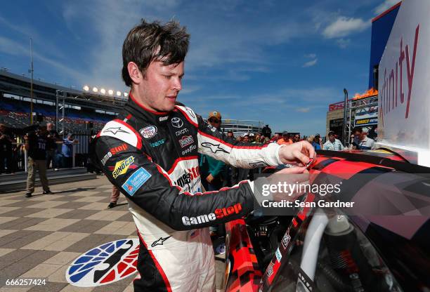 Erik Jones, driver of the GameStop/GAEMS Toyota, affixes the winners decal to his car in Victory Lane after winning the NASCAR XFINITY Series My...