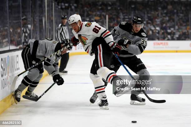 Marian Hossa of the Chicago Blackhawks is hit by Brayden McNabb and Paul LaDue of the Los Angeles Kings during the first period of a game at Staples...