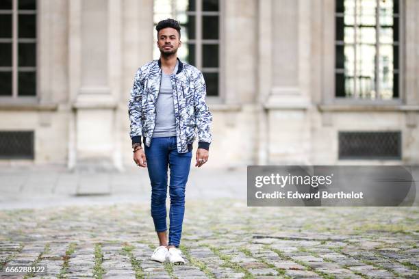 Theo Kimbaloula, fashion blogger, wears a Sand Copenhagen bomber jacket, an Asos t-shirt, Asos blue jeans, and Jules white sneakers shoes, at the...