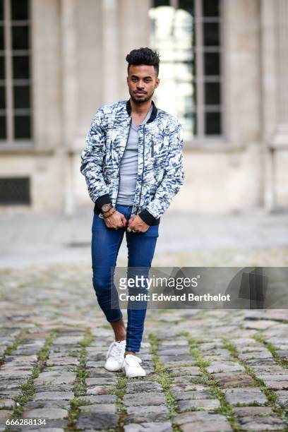 Theo Kimbaloula, fashion blogger, wears a Sand Copenhagen bomber jacket, an Asos t-shirt, Asos blue jeans, and Jules white sneakers shoes, at the...