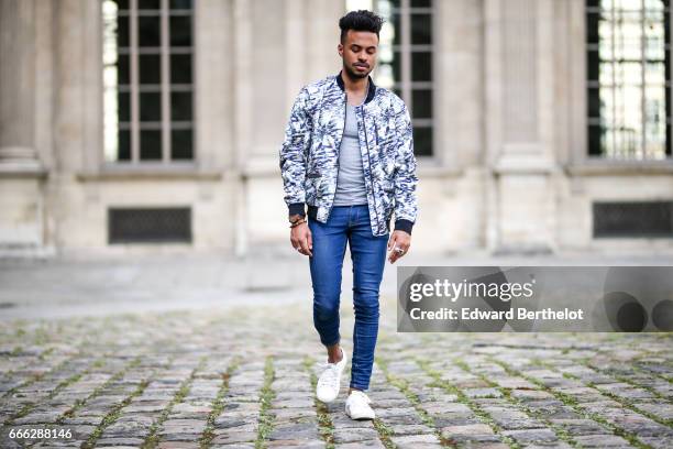 Theo Kimbaloula, fashion blogger, wears a Sand Copenhagen bomber jacket, an Asos t-shirt, Asos blue jeans, and Jules white sneakers shoes, at the...