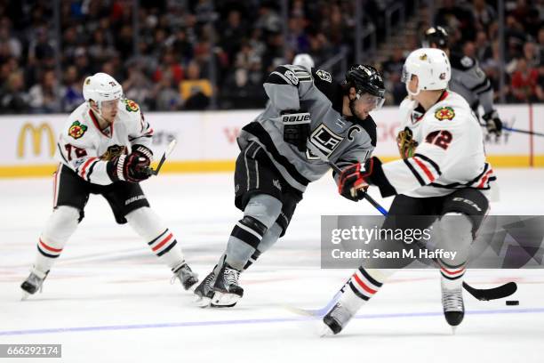 Anze Kopitar of the Los Angeles Kings skates with the puck between Gustav Forsling and Artemi Panarin of the Chicago Blackhawks during the second...