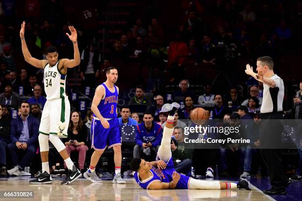 Giannis Antetokounmpo of the Milwaukee Bucks fouls Timothe Luwawu-Cabarrot as T.J. McConnell of the Philadelphia 76ers looks on during the fourth...