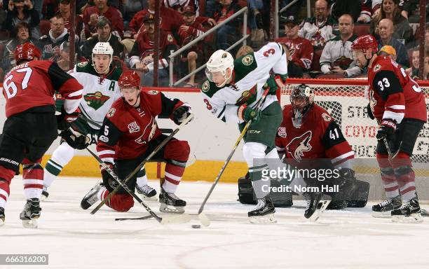 Lawson Crouse of the Arizona Coyotes and Charlie Coyle of the Minnesota Wild battle for the puck in front of goalie Mike Smith, Connor Murphy and...