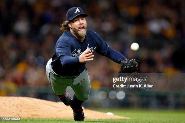 Dickey of the Atlanta Braves makes a diving play to get the out in the sixth inning against the Pittsburgh Pirates at PNC Park on April 8, 2017 in...