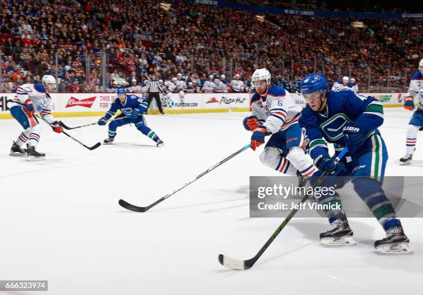 Adam Larsson of the Edmonton Oilers checks Drew Shore of the Vancouver Canucks during their NHL game at Rogers Arena April 8, 2017 in Vancouver,...