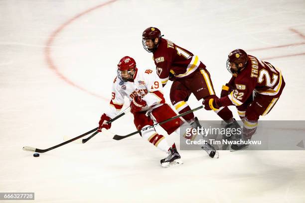 Troy Terry of the Denver Pioneers grabs the puck ahead of Blake Young and Jared Thomas of the Minnesota-Duluth Bulldogs in the third period during...