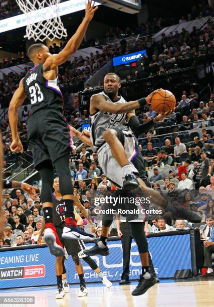 Jonathon Simmons of the San Antonio Spurs looks to pass off as he drives past Wesley Johnson of the Los Angeles Clippers at AT&T Center on April 8,...