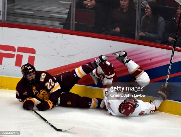 Denver Pioneers defenseman Tariq Hammond and Minnesota-Duluth Bulldogs center Jared Thomas slam into the boards during the third period of the NCAA...