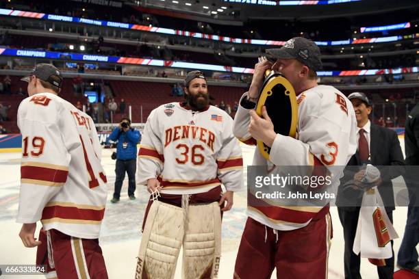 Denver Pioneers goalie Tanner Jaillet looks on as Denver Pioneers defenseman Tariq Hammond kisses the trophy after their win over the...