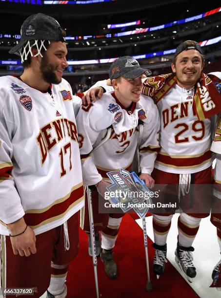 Rudy Junda and Brad Hawkinson of the Denver Pioneers hug teammate Tariq Hammond who was injured in the third period against the Minnesota-Duluth...