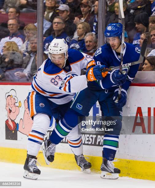 Matthew Benning of the Edmonton Oilers check Jayson Megna of the Vancouver Canucks into the end boards in NHL action on April 8, 2017 at Rogers Arena...