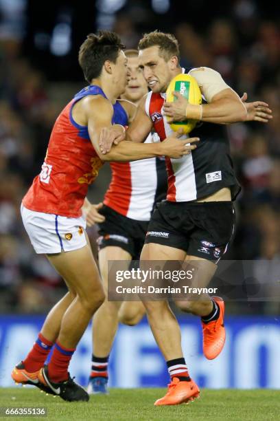 Luke Dunstan of the Saints shrugs the tackle of Hugh McCluggage of the Lions during the round three AFL match between the St Kilda Saints and the...