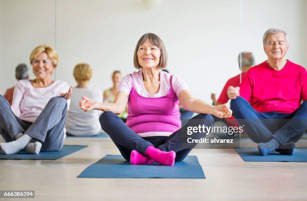 lächelnder senior mann und frauen, die yoga im fitness-studio - senior yoga stock-fotos und bilder
