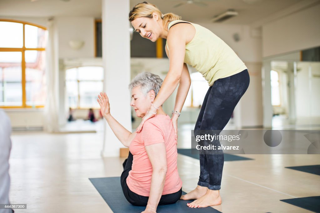 Lehrer helfen senior Frau dabei yoga