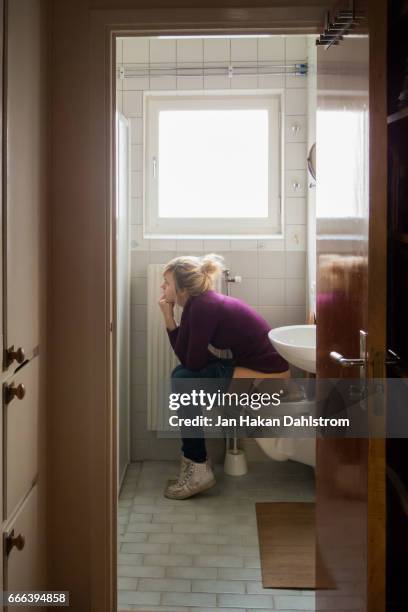 young woman sits on toilet seat - people peeing stockfoto's en -beelden