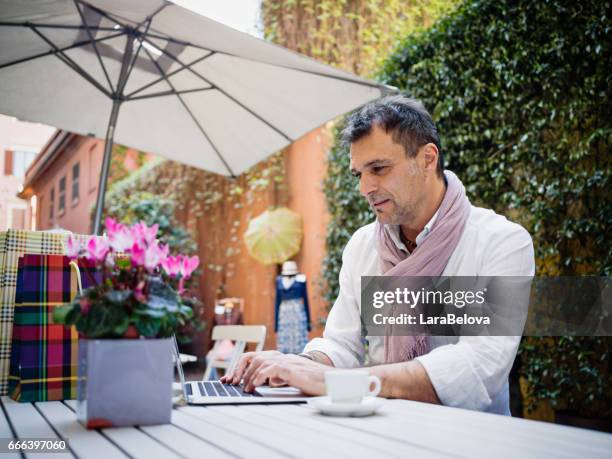 volwassen man met laptop in sidewalk café - zuid europa stockfoto's en -beelden