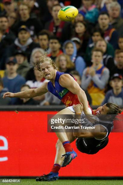 Daniel Rich of the Lions gets a kick away as Maverick Weller of the Saints lays a taclkle during the round three AFL match between the St Kilda...