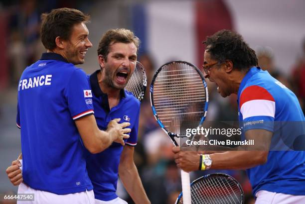 Julien Benneteau of France celebrates with Nicolas Mahut and captain Yannick Noah after all three went on court to play a point in the singles match...