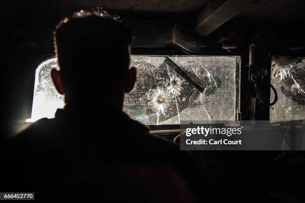 An Iraqi Emergency Response Division soldier is silhouetted by an oncoming vehicle as he drives a Humvee with bullet damaged windows in west Mosul on...