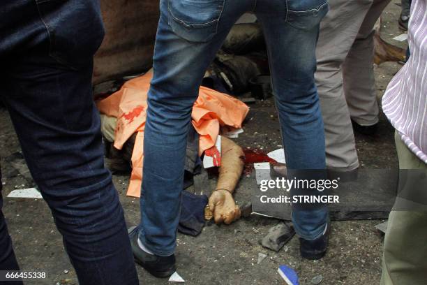 Graphic content / Egyptians gather around a body in a street near a church in Alexandria after a bomb blast struck worshippers gathering to celebrate...