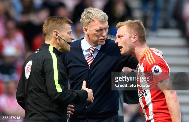 Sebastian Larsson of Sunderland reacts after being sent off with fourth official Mike Jones and David Moyes, Manager of Sunderland for a challenge on...