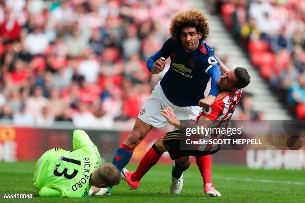 Manchester United's Belgian midfielder Marouane Fellaini tangles with Sunderland's Costa Rican defender Bryan Oviedo to get to a ball saved by...