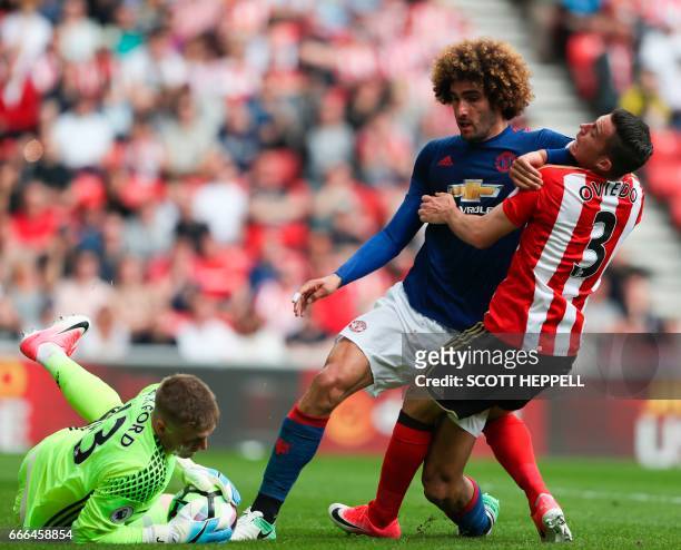 Manchester United's Belgian midfielder Marouane Fellaini tangles with Sunderland's Costa Rican defender Bryan Oviedo to get to a ball saved by...