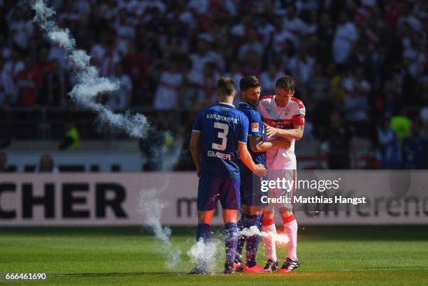 Christian Gentner of Stuttgart, Benedikt Gimber and Dennis Kempe of Karlsruhe evade a signal rocket after the Second Bundesliga match between VfB...