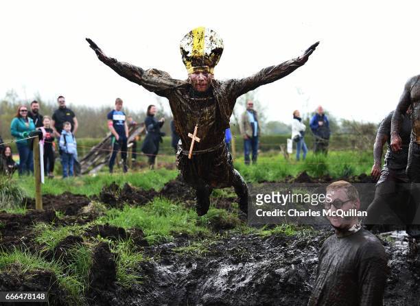 Man dressed as the Pope jumps into a pool of mud as competitors take part in the annual McVities Mud Madness 8km cross country run on April 9, 2017...