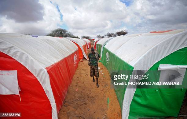 Newly displaced Somali man walks between tents at a camp in the Kaxda district, outskirts of Mogadishu, on April 9, 2017. Somalia, a Horn of Africa...