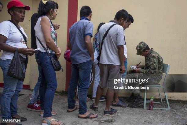 Displaced residents wait in line to provide information to a member of the military at a disaster relief center after landslides in Mocoa, Putumayo,...
