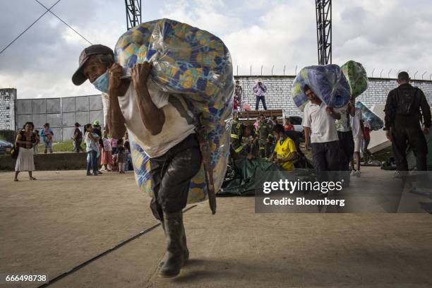 Displaced residents carry bedding to tents at a disaster relief center after landslides in Mocoa, Putumayo, Colombia, on Monday, April 3, 2017....