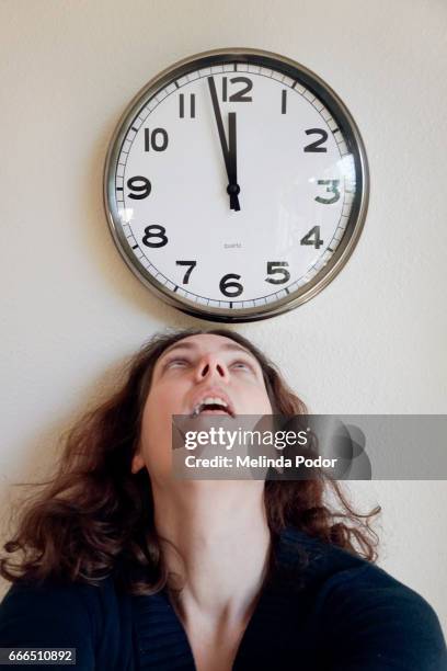 woman looking up at a clock, close to noon - office hour stock pictures, royalty-free photos & images