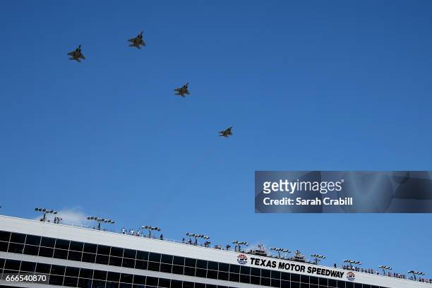Military aircraft perform a flyover in the 'missing man formation' prior to the Monster Energy NASCAR Cup Series O'Reilly Auto Parts 500 at Texas...
