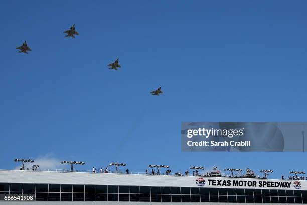 Military aircraft perform a flyover in the 'missing man formation' prior to the Monster Energy NASCAR Cup Series O'Reilly Auto Parts 500 at Texas...