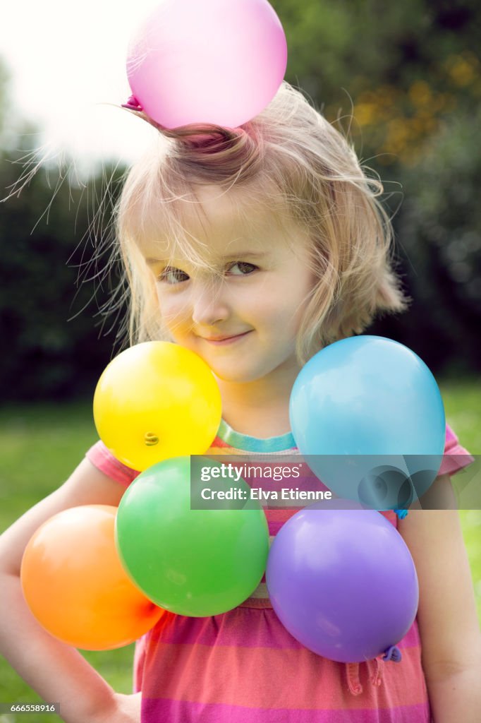 Multi colored balloons stuck to a child through static electricity